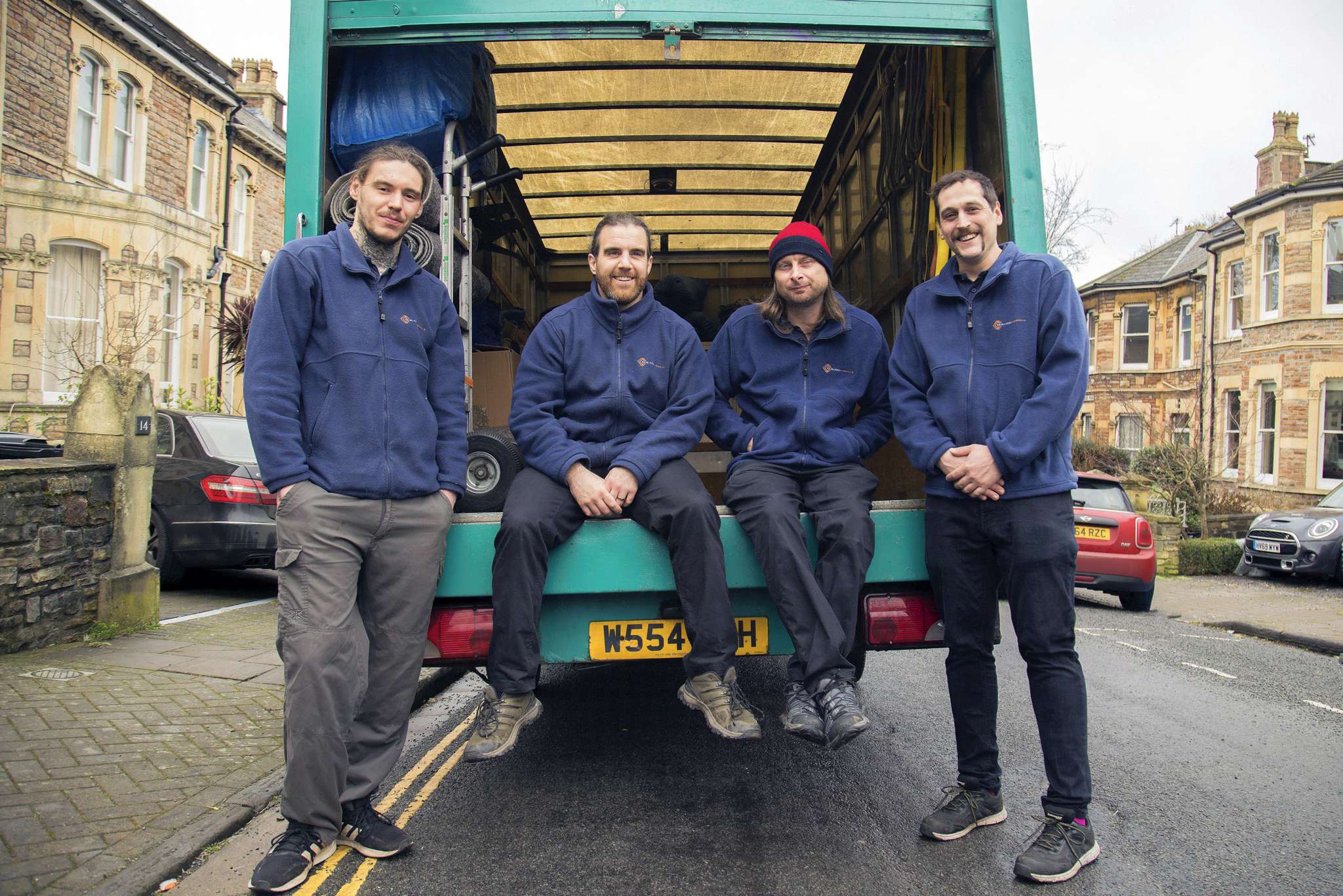 The Painless Removals crew sitting on the back of a removal van on a Bristol residential street
